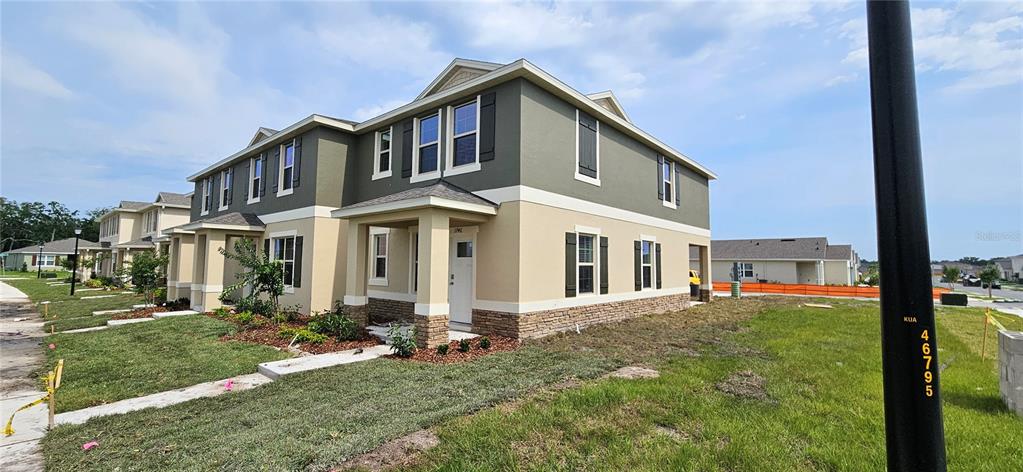 A two-story townhouse with a tan and olive exterior, stone accents, and a covered porch — 1746 RED CANYON DRIVE, KISSIMMEE, FL