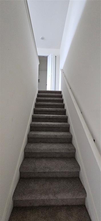 A straight staircase with gray carpet leads upward to a doorway in a white hallway — 1746 RED CANYON DRIVE, KISSIMMEE, FL