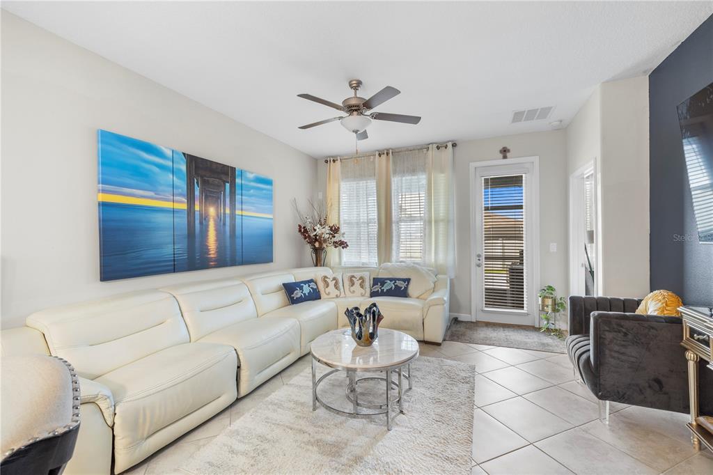 A living room features a white sectional sofa, a round coffee table, and large wall art — 9611 IVORY DRIVE, SUN CITY CENTER, FL