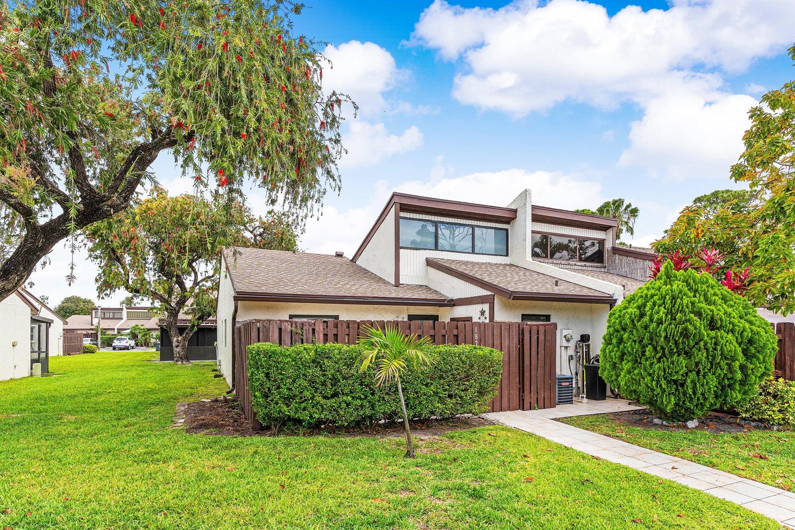 A two-story townhouse with a brown wooden fence, a small palm tree, and green landscaping — 1875 Abbey Road, West Palm Beach FL 33415, WEST PALM BEACH, FL