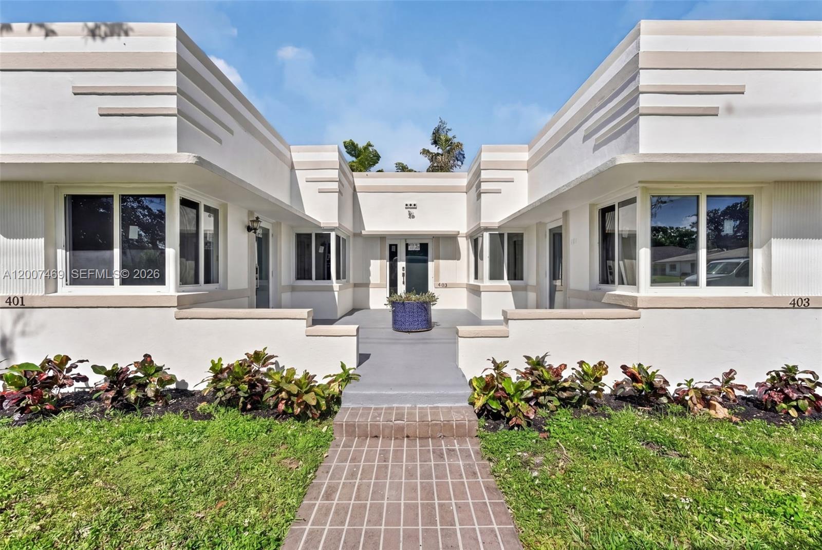 A symmetrical white Art Deco building features a central walkway leading to a shared entrance — FORT LAUDERDALE, FL