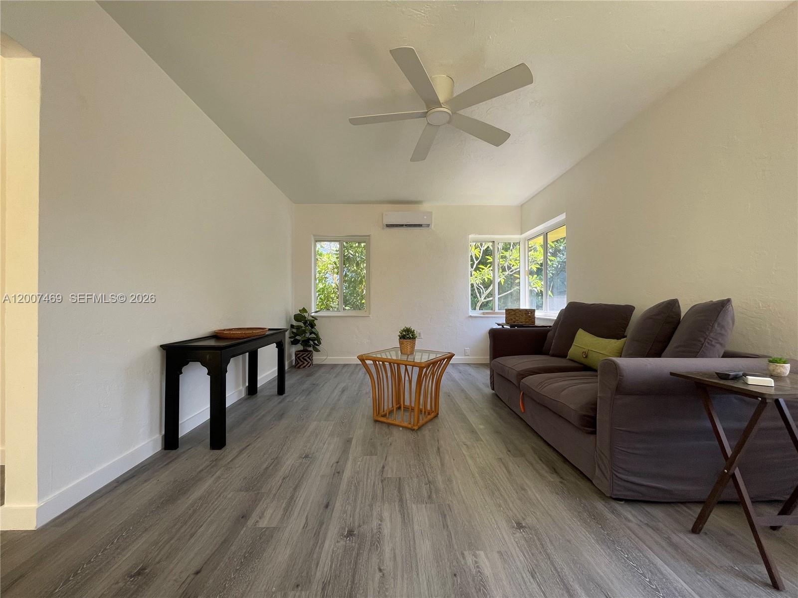 A living room features gray wood-look flooring, a dark sofa, and a ceiling fan — FORT LAUDERDALE, FL