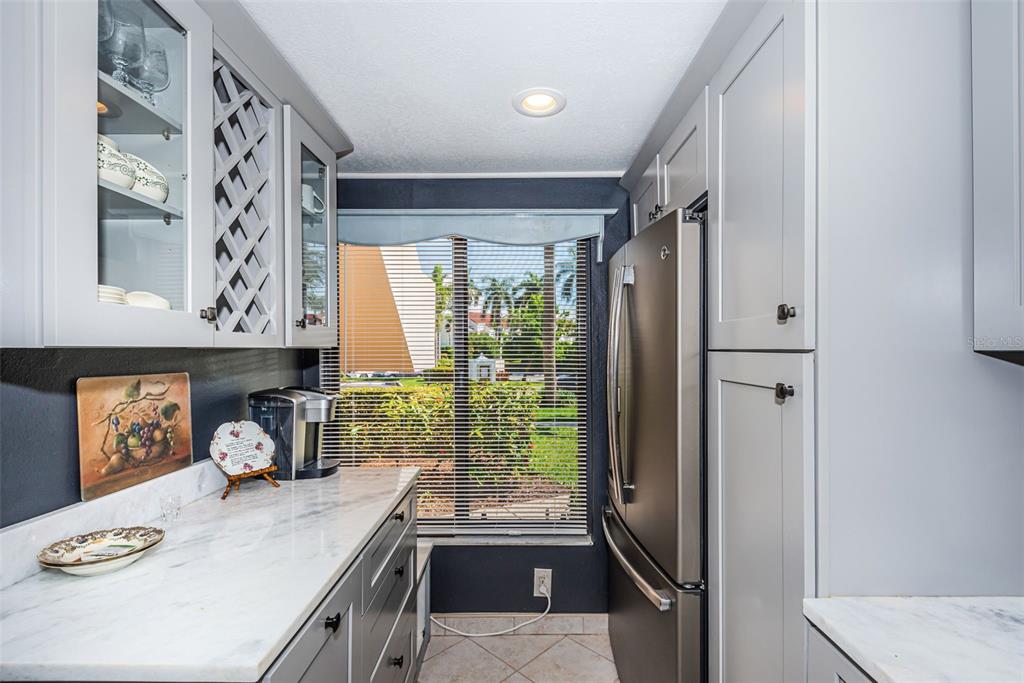 A kitchen features gray cabinets, marble countertops, stainless steel appliances, and a window with blinds — 6281 BAHIA DEL MAR BOULEVARD UNIT 105, ST PETERSBURG, FL