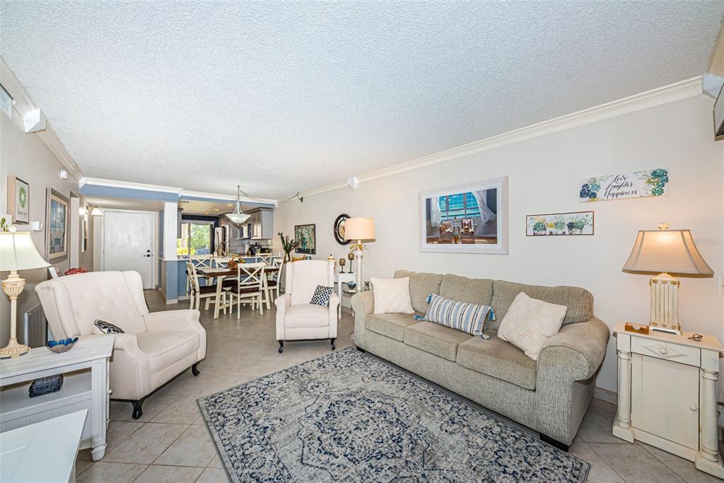 A living room features a beige sofa, two white armchairs, and an adjacent dining area — 6281 BAHIA DEL MAR BOULEVARD UNIT 105, ST PETERSBURG, FL