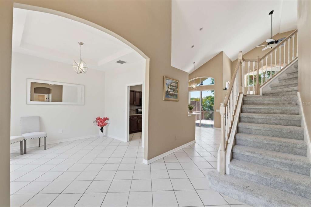 A tiled entryway features a staircase with carpeted steps and a view into the living area — 1837 BRILAND STREET, TARPON SPRINGS, FL