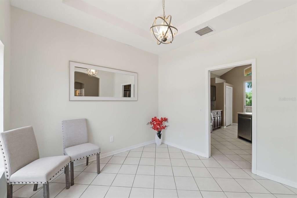 A dining room with light tile floors, two gray chairs, a mirror, and a chandelier — 1837 BRILAND STREET, TARPON SPRINGS, FL