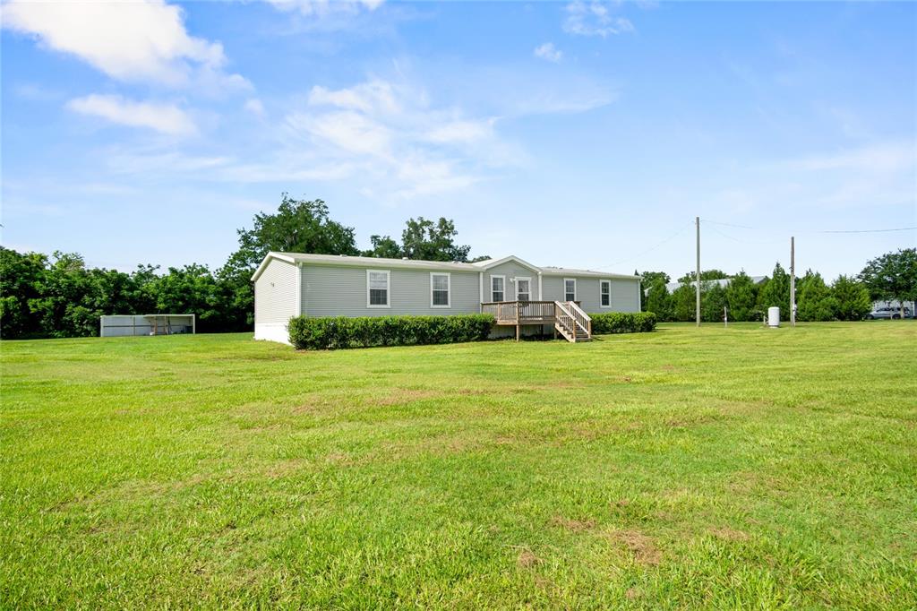 A light-colored manufactured home sits in the middle of a large, grassy field — 39670 WILDS RD, DADE CITY, FL