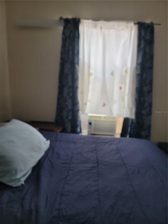 A bedroom features a bed with a dark blue comforter and a window with curtains — 17349 SILVER CREEK COURT, CLERMONT, FL