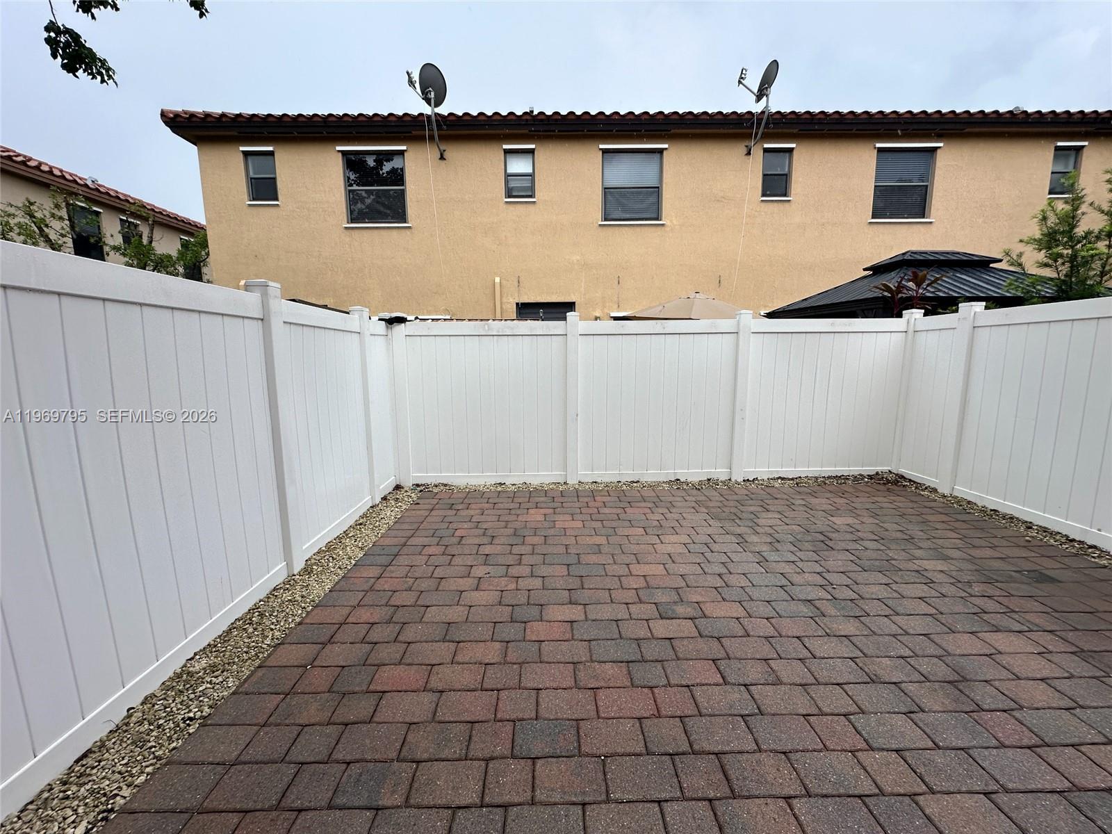 A paved patio is enclosed by a white vinyl fence in front of a building — 9374 W 32nd Ln, Hialeah FL 33018, HIALEAH, FL