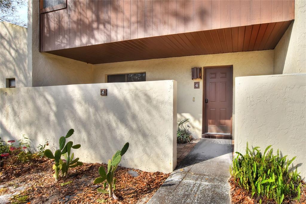 The exterior of a residential unit features a brown door, stucco walls, and desert landscaping — 1880 N CRYSTAL LAKE DRIVE UNIT 4, LAKELAND, FL