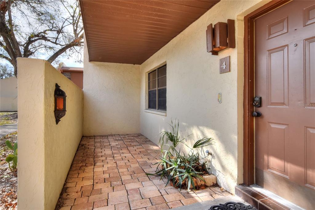 A paved entryway features a brown door, a wall-mounted lantern, and a small potted plant — 1880 N CRYSTAL LAKE DRIVE UNIT 4, LAKELAND, FL