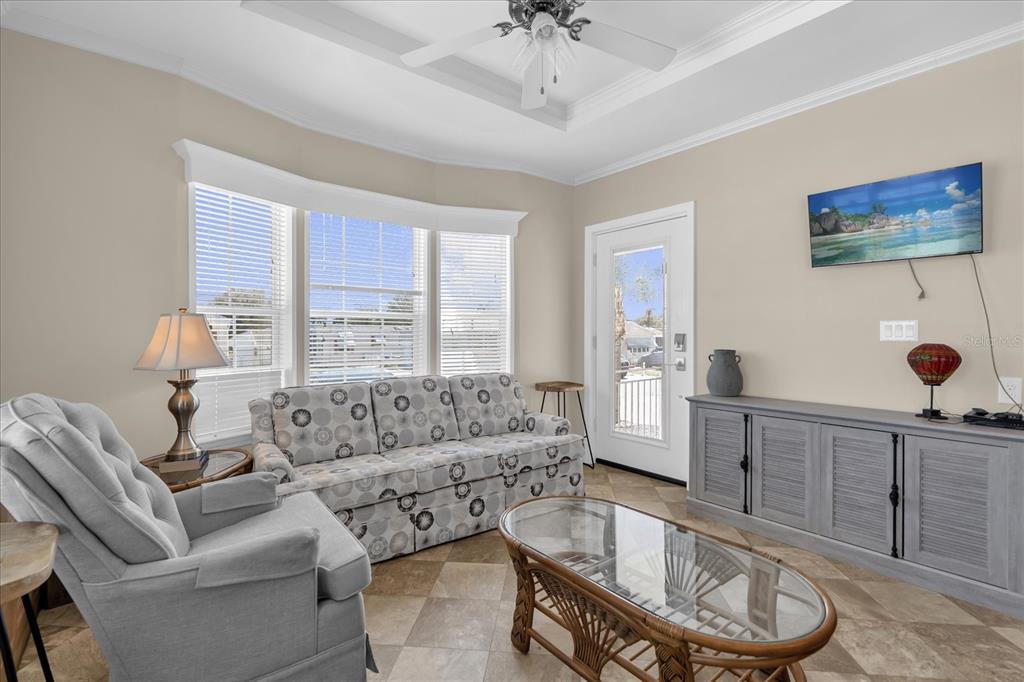 A living room features a patterned sofa, a gray armchair, a glass coffee table, and television — 1039 CENTER CREST BOULEVARD, DAVENPORT, FL