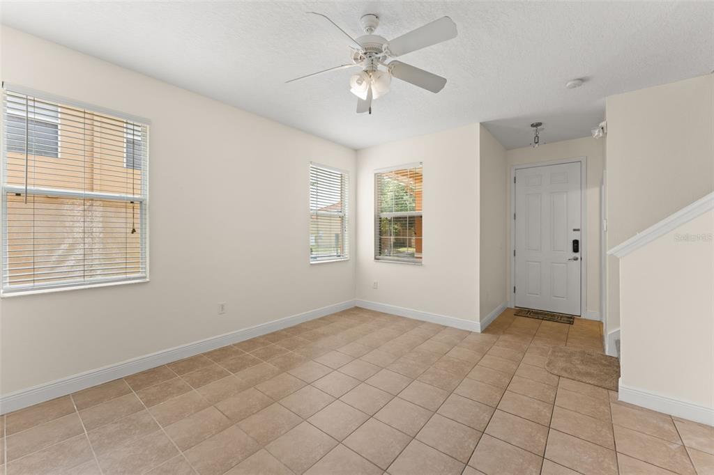 A room with beige tile flooring, a ceiling fan, and a white front door — 2691 ANDROS LANE, KISSIMMEE, FL