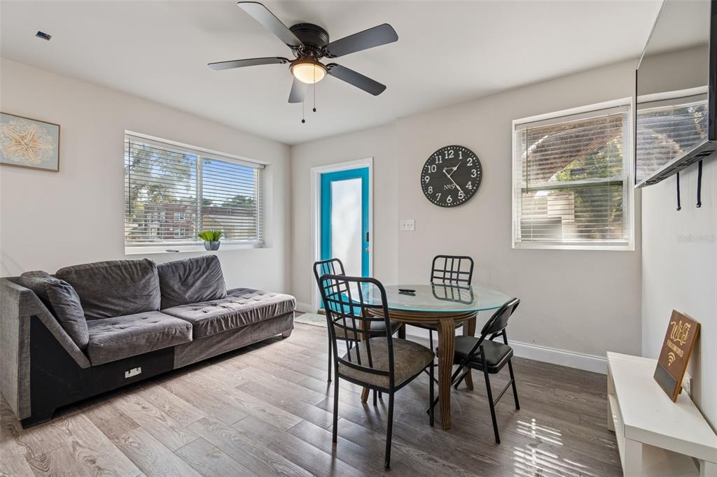 A living and dining area features a gray sofa, glass table, and a blue door — 1006 E 26TH AVENUE, TAMPA, FL
