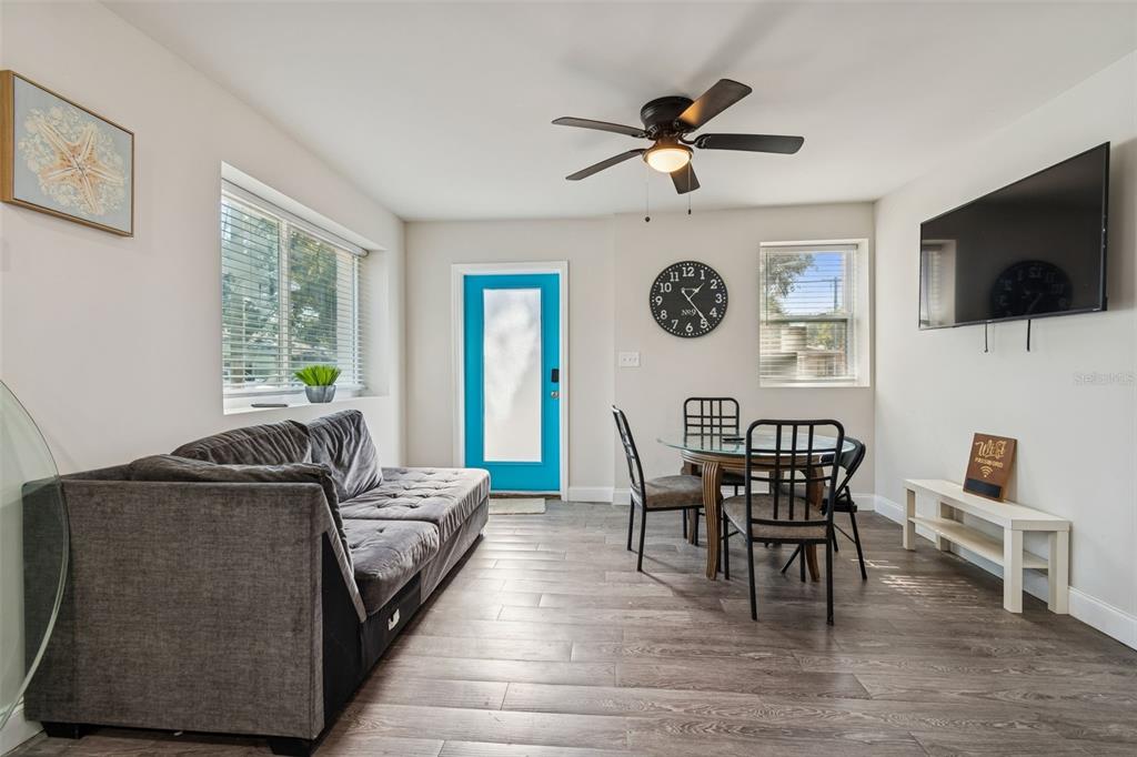 A living and dining area features a gray sofa, glass table, and a blue door — 1006 E 26TH AVENUE, TAMPA, FL