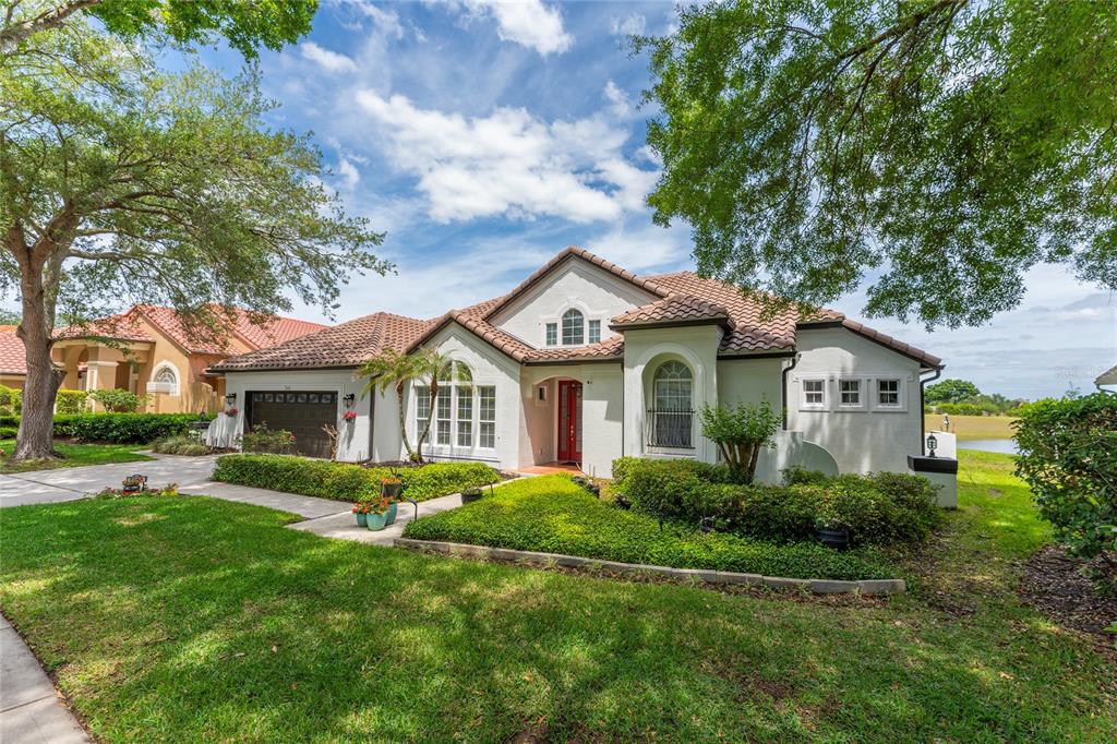 A single-story stucco house with a tile roof, red front door, and manicured landscaping — 7665 MOUNT CARMEL DRIVE, ORLANDO, FL