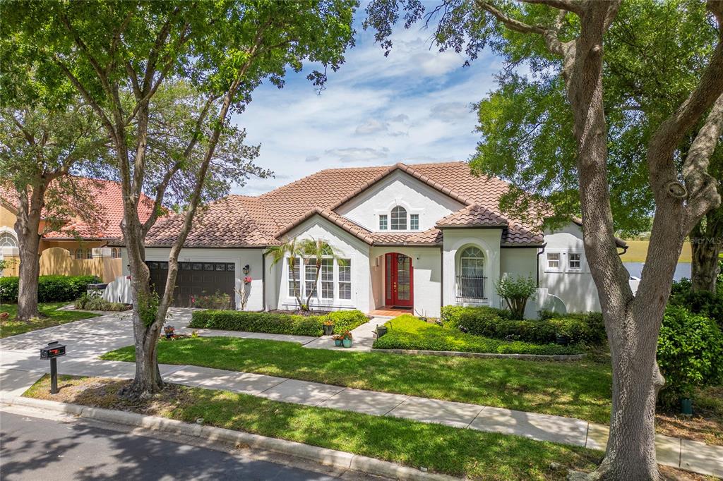 A single-story house with a white brick exterior, red front door, and tiled roof — 7665 MOUNT CARMEL DRIVE, ORLANDO, FL