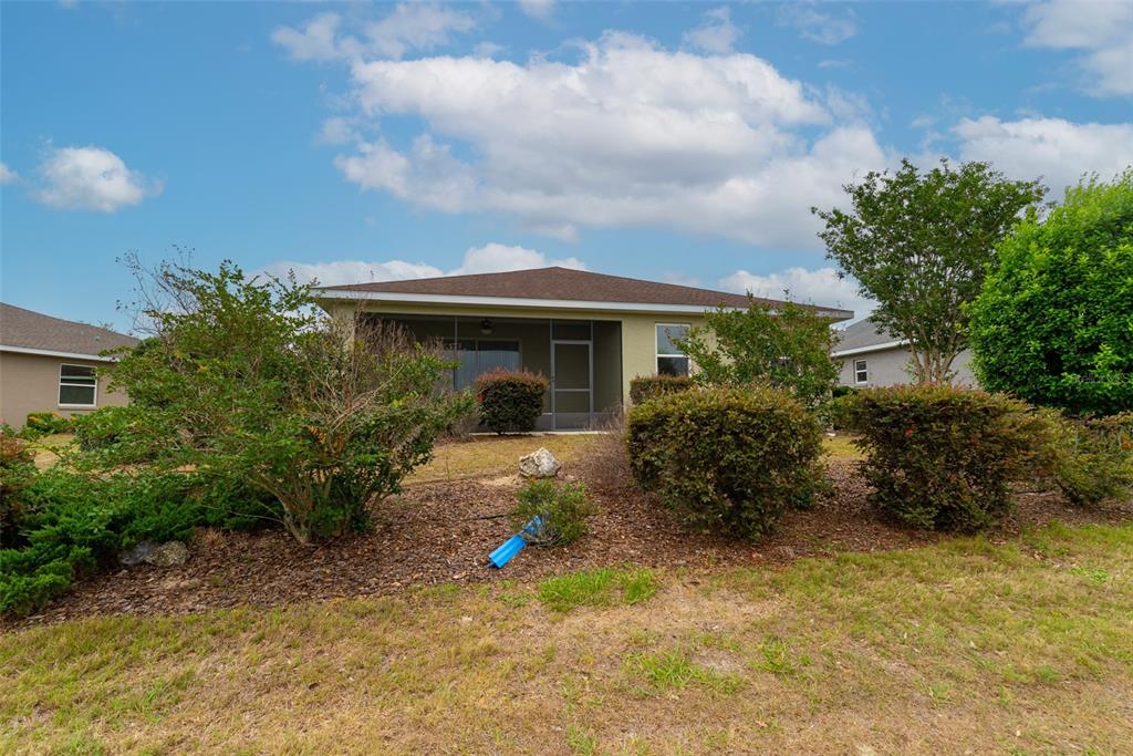 The exterior of a single-story house features a screened-in back porch and landscaped yard — 10067 SW 89TH LOOP, OCALA, FL