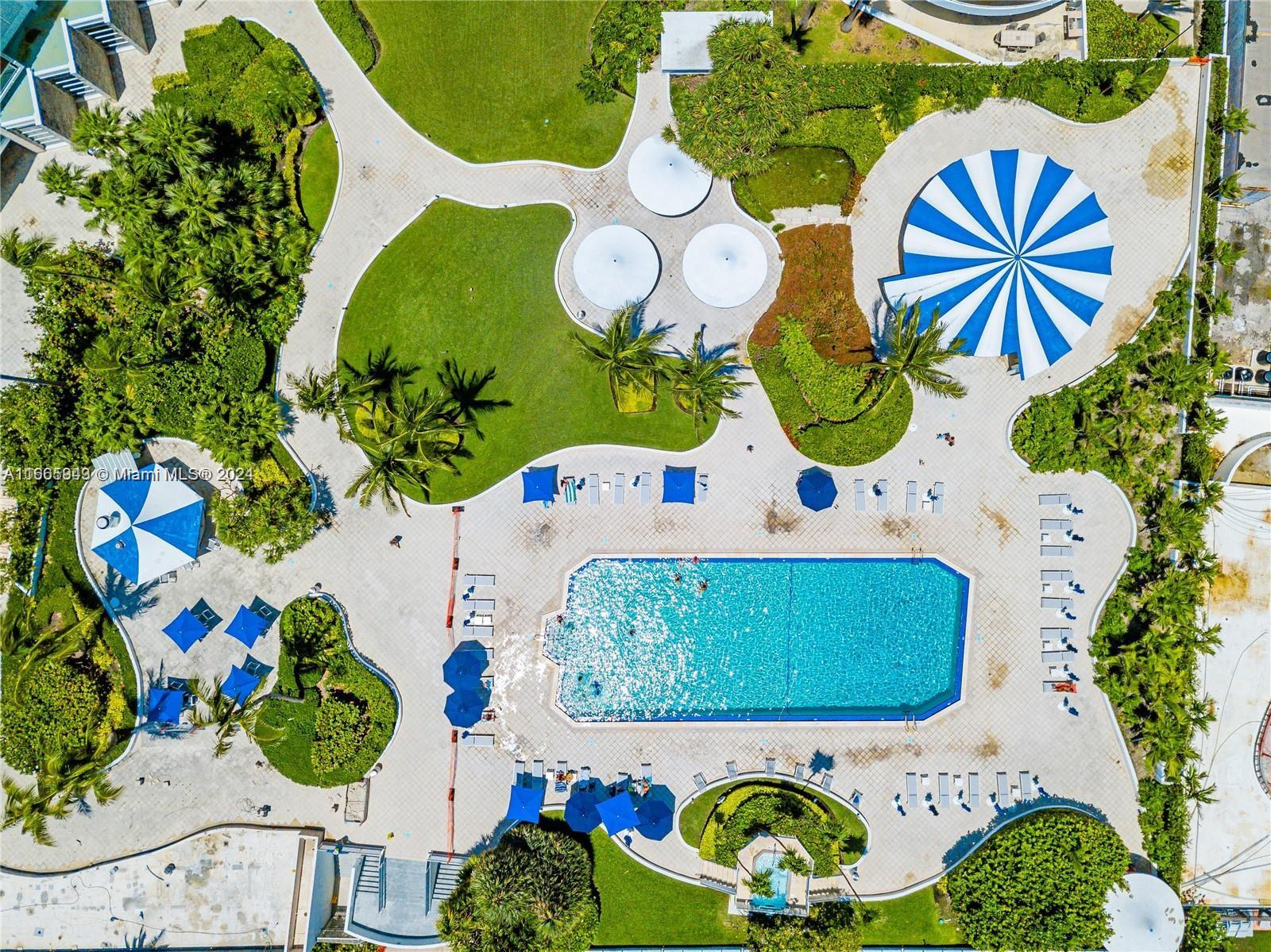 An aerial view shows a swimming pool surrounded by lounge chairs, umbrellas, and landscaping — 5161 Collins Ave # 505, Miami Beach FL 33140, MIAMI BEACH, FL