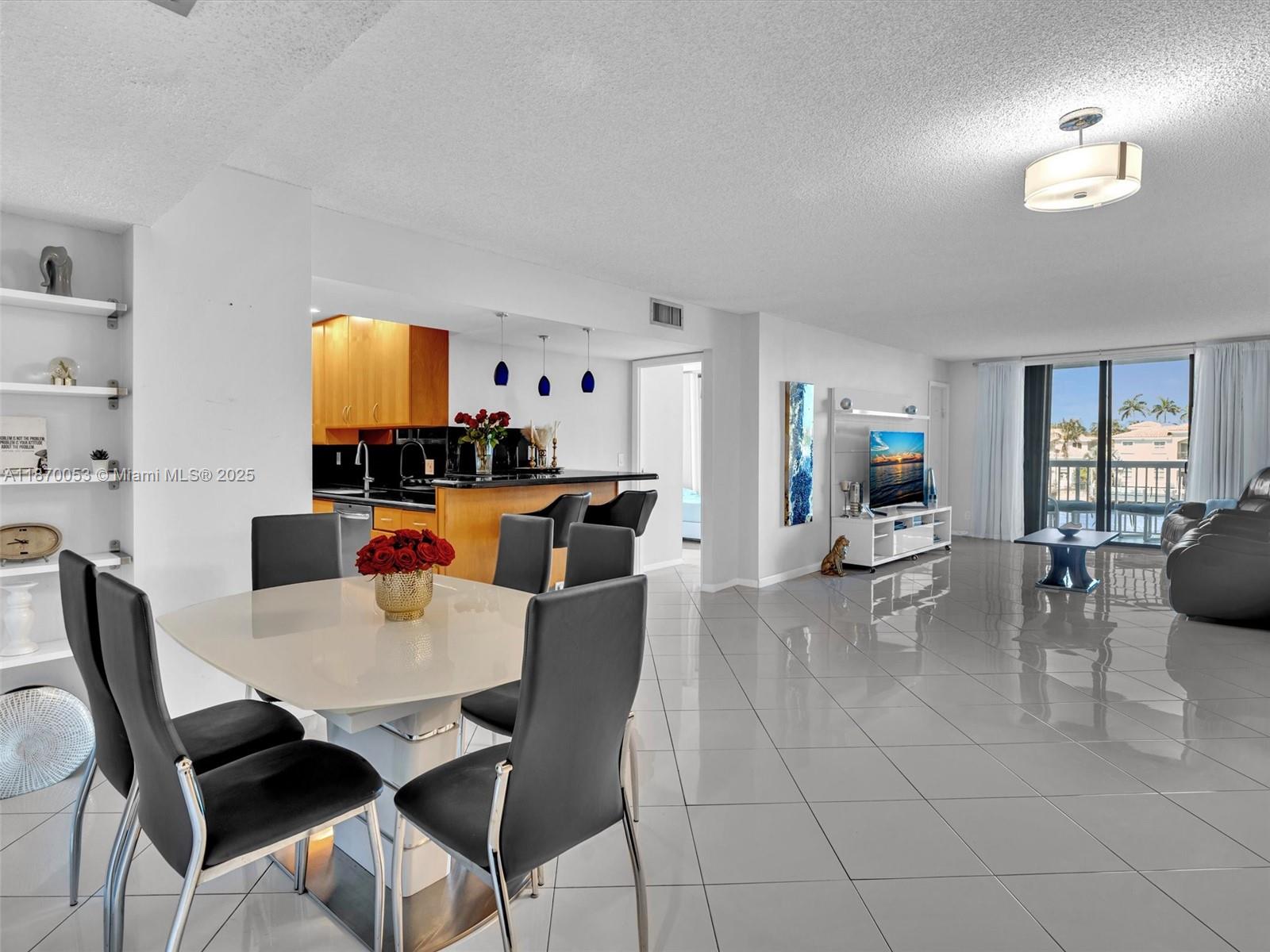 An open-concept living and dining area features white tile floors, a kitchen, and balcony access — 1500 S Ocean Dr # 3E, Hollywood FL 33019, HOLLYWOOD, FL