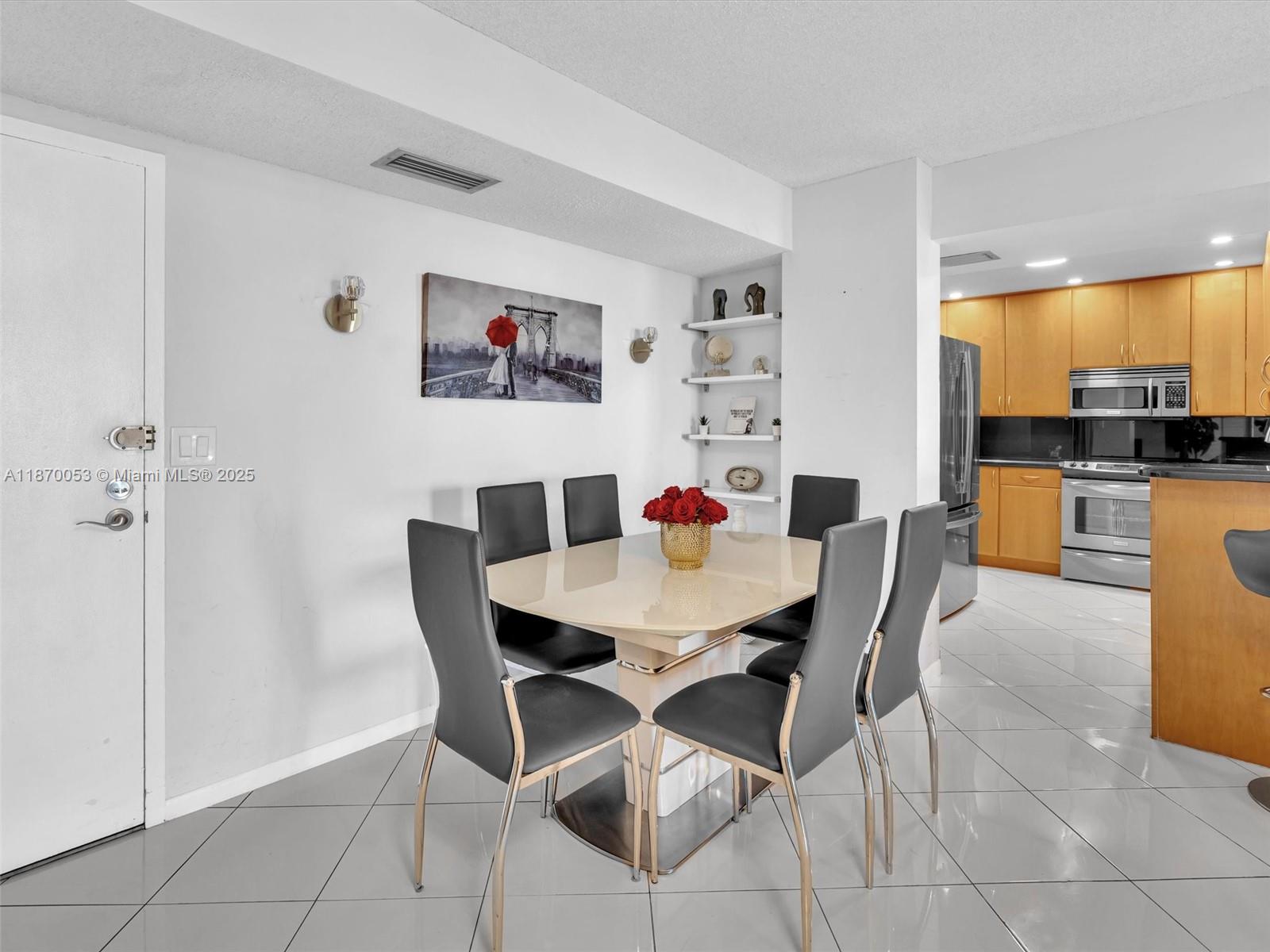 A dining area features a glass table with six chairs, wall art, and open shelving — 1500 S Ocean Dr # 3E, Hollywood FL 33019, HOLLYWOOD, FL