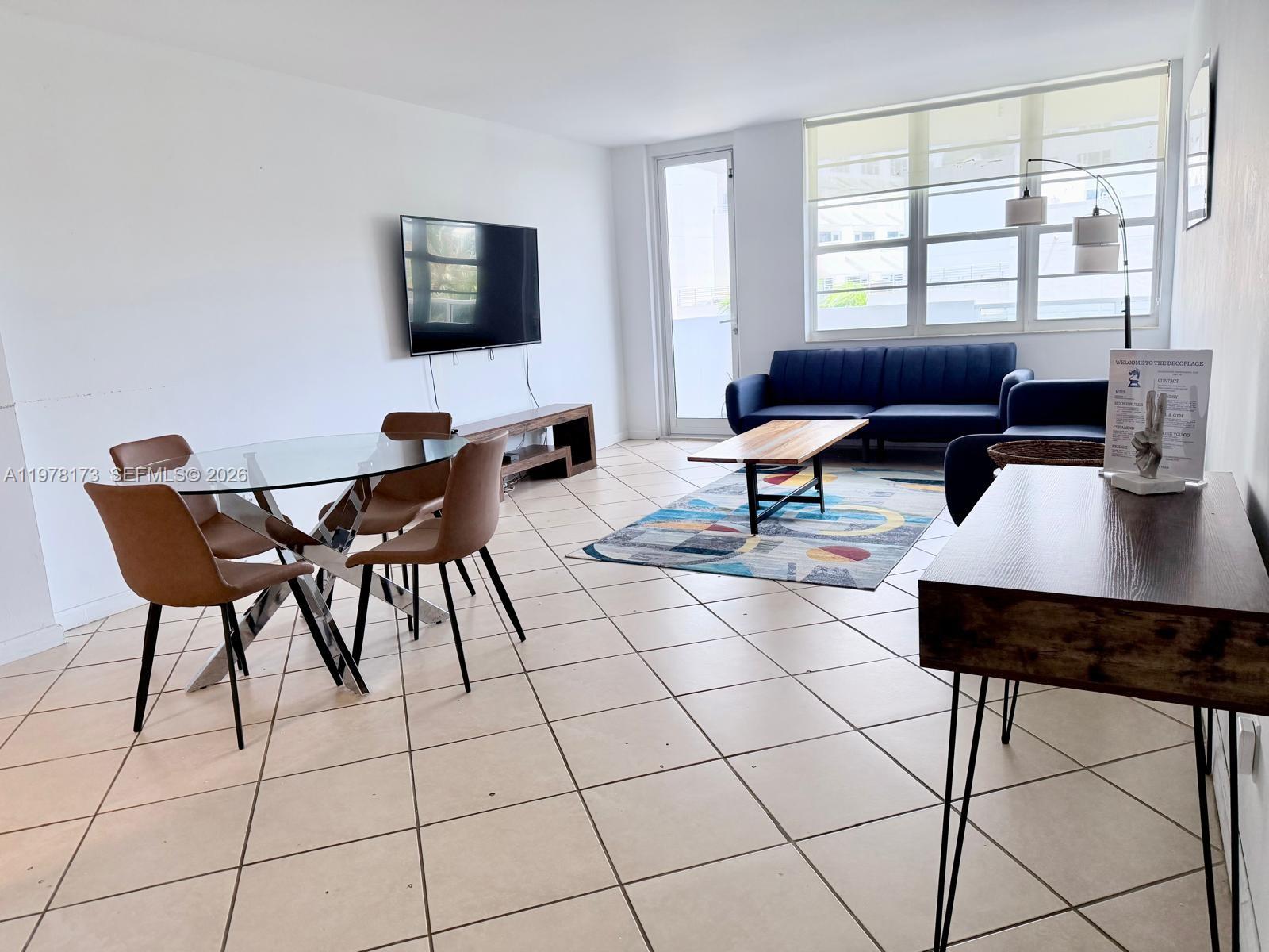 A living and dining area features tile floors, a glass table, and a blue sofa — 100 Lincoln Rd # 441, Miami Beach FL 33139, MIAMI BEACH, FL