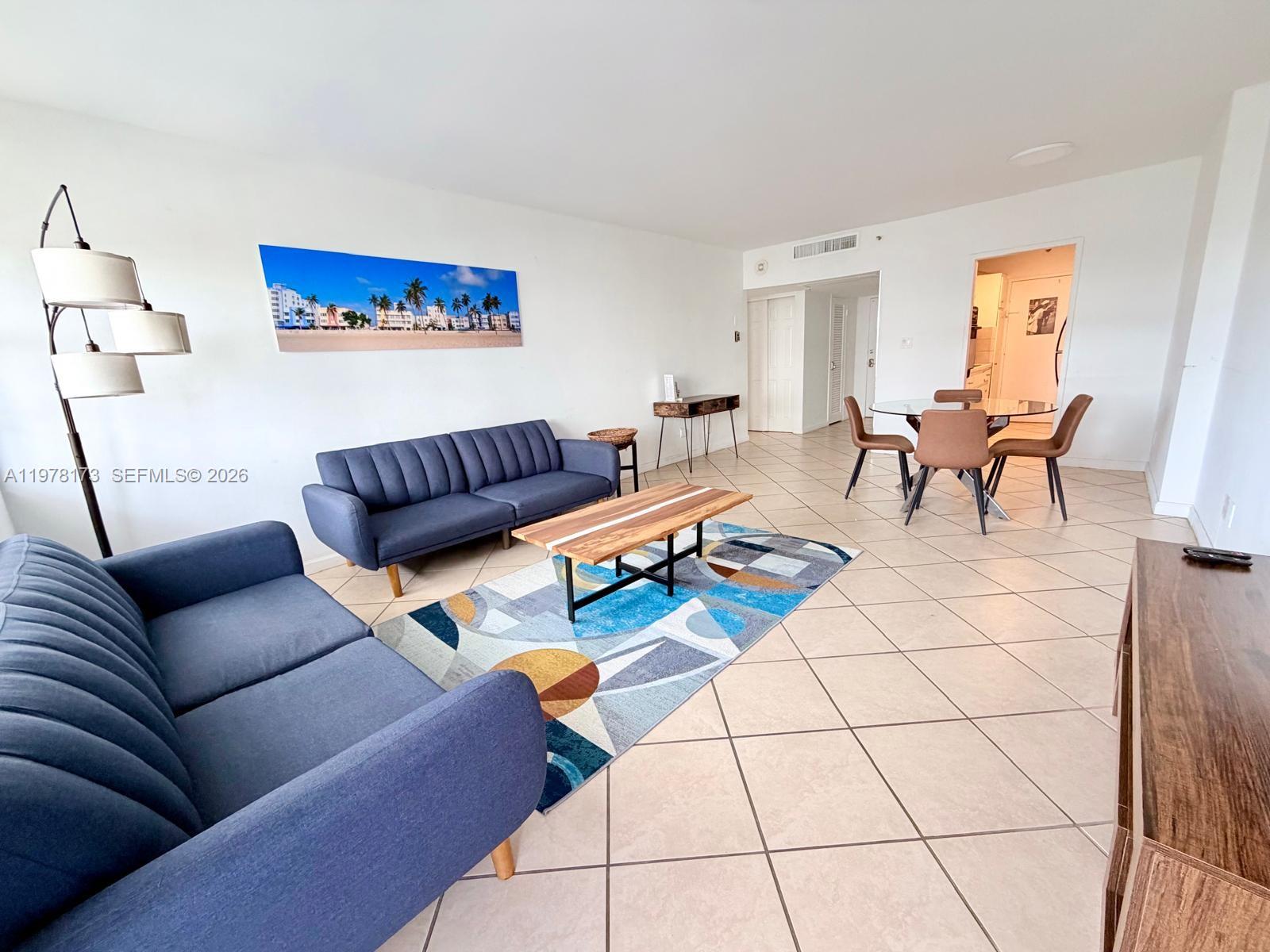 A living and dining area features blue sofas, a patterned rug, and tile flooring — 100 Lincoln Rd # 441, Miami Beach FL 33139, MIAMI BEACH, FL
