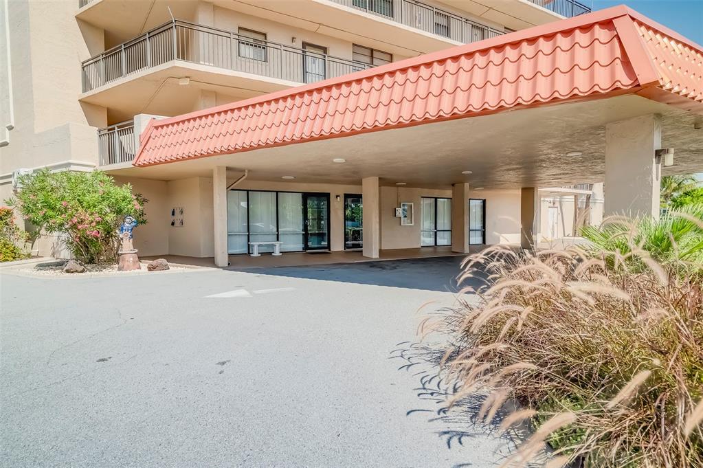 The exterior of a multi-story building features a covered entrance with a red tile roof — 17580 GULF BOULEVARD UNIT 412, REDINGTON SHORES, FL