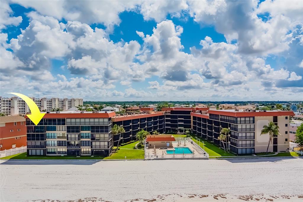 An aerial view of a beachfront condominium building with a pool and a yellow arrow — 17580 GULF BOULEVARD UNIT 412, REDINGTON SHORES, FL