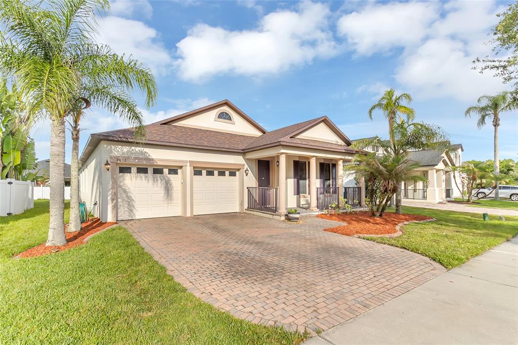 A single-story house with a brick paver driveway, two-car garage, and palm trees — 9837 OLD PATINA WAY, ORLANDO, FL