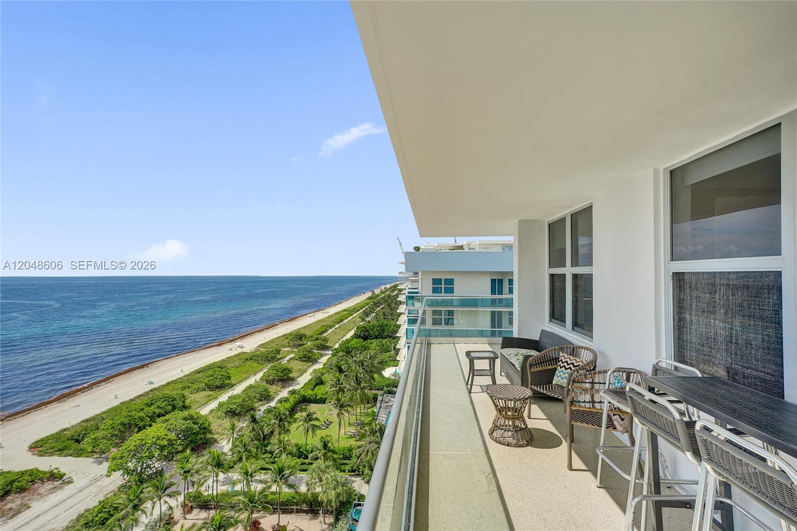 A balcony with outdoor furniture overlooks a sandy beach and the ocean — 9225 Collins Ave # 1402, Surfside FL 33154, SURFSIDE, FL