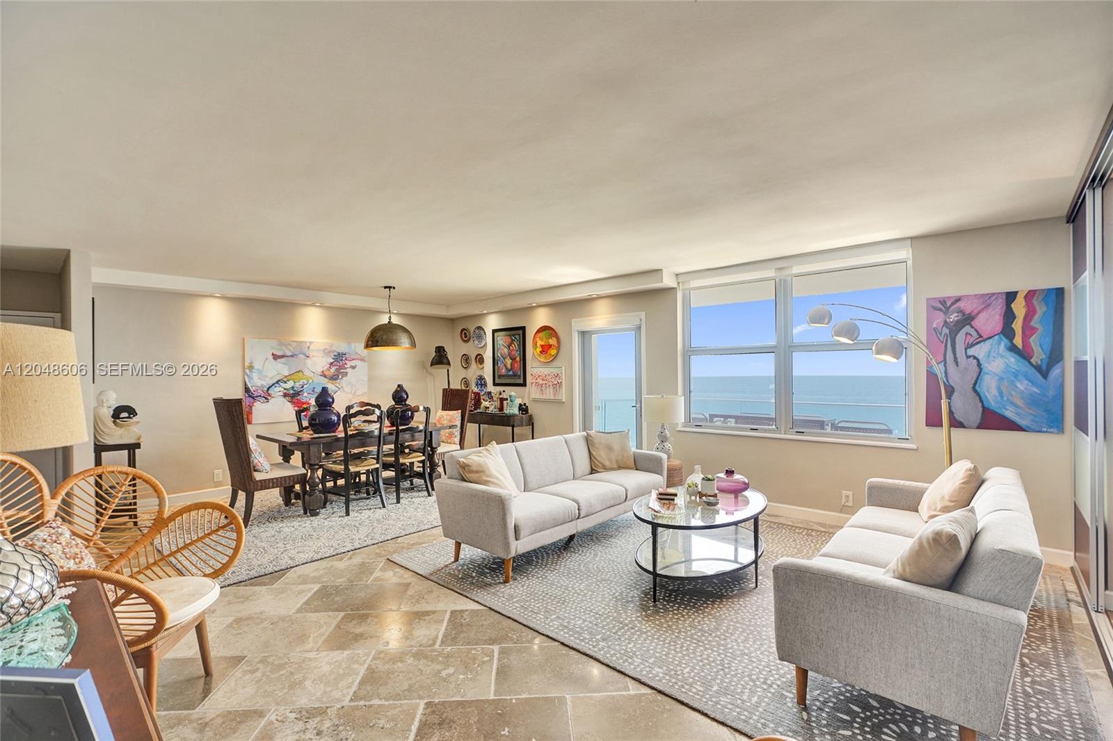 An open-concept living and dining room features tile floors, neutral furniture, and ocean views — 9225 Collins Ave # 1402, Surfside FL 33154, SURFSIDE, FL