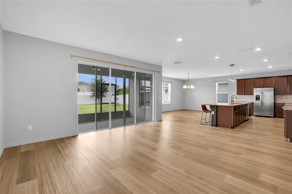 An open-concept living area with light wood floors, a kitchen island, and sliding glass doors — 777 OGELTHORPE DRIVE, DAVENPORT, FL