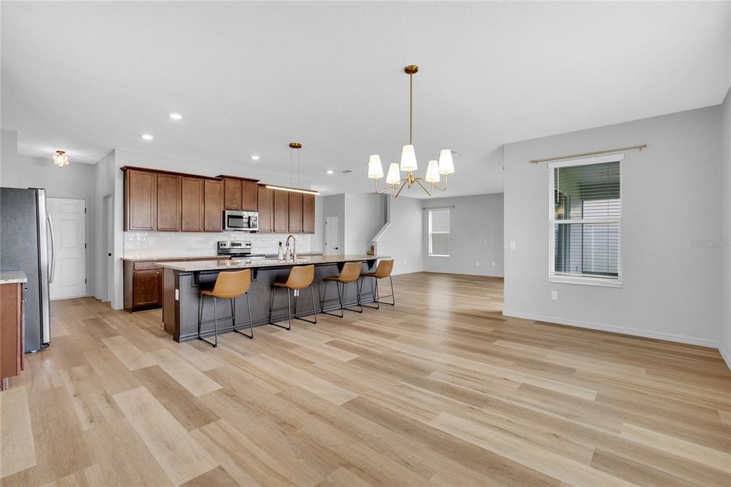 A kitchen with dark wood cabinets and a large island opens into a spacious living area — 777 OGELTHORPE DRIVE, DAVENPORT, FL