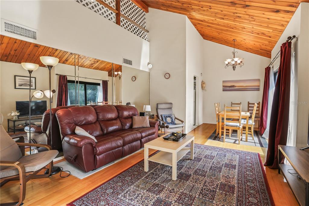 A living and dining area features vaulted wood ceilings, hardwood floors, and a large rug — 220 PASS KEY ROAD UNIT 220, SARASOTA, FL
