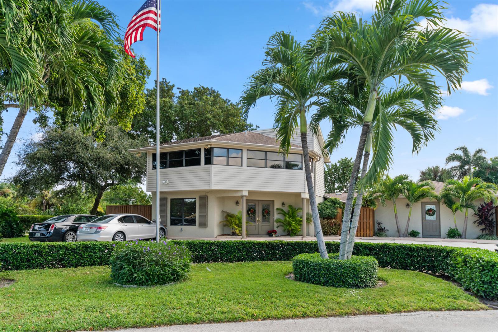 A two-story building with light siding, a flag pole, and palm trees in the front yard — 2016 Joy-rene Lane, North Palm Beach FL 33408, NORTH PALM BEACH, FL