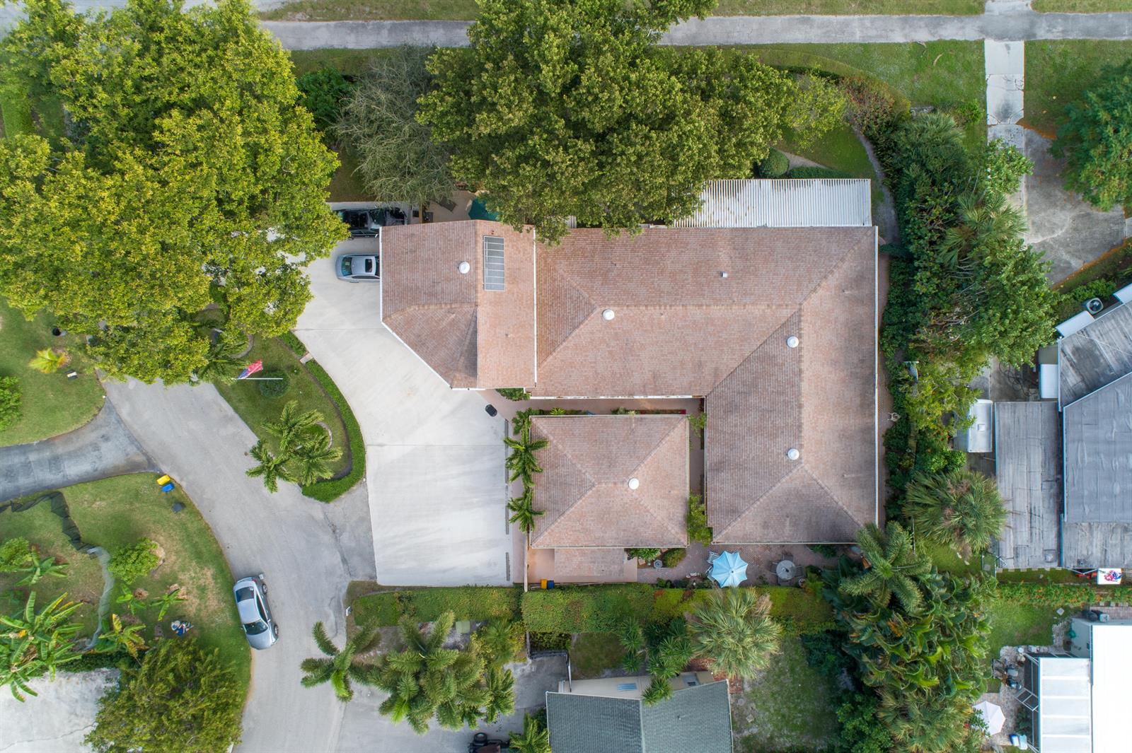 An aerial view shows a house with a brown roof, concrete driveway, and surrounding trees — 2016 Joy-rene Lane, North Palm Beach FL 33408, NORTH PALM BEACH, FL