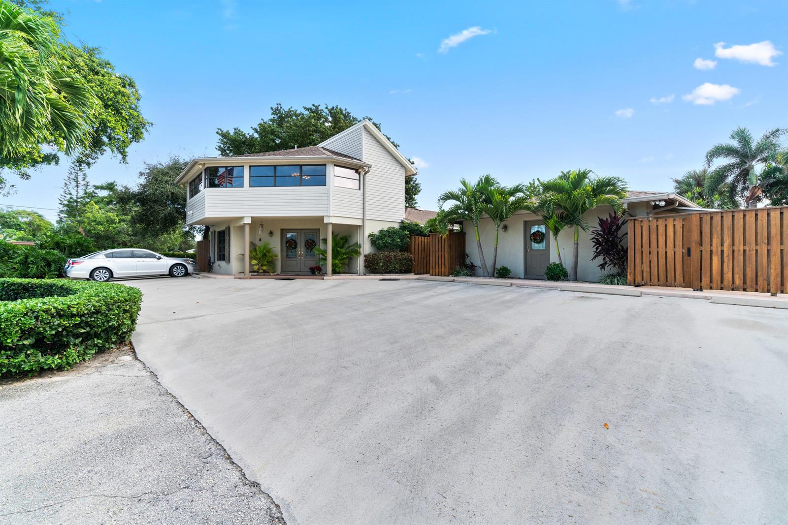 A two-story house with a large concrete driveway, palm trees, and a wooden fence — 2016 Joy-rene Lane, North Palm Beach FL 33408, NORTH PALM BEACH, FL