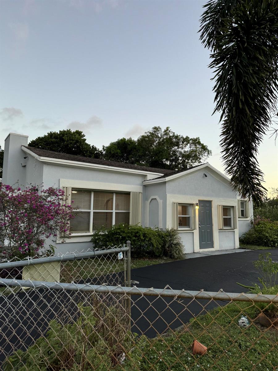 A single-story house with a light gray exterior, a dark front door, and a chain-link fence — 701 SW 8th Avenue, Delray Beach FL 33444, DELRAY BEACH, FL