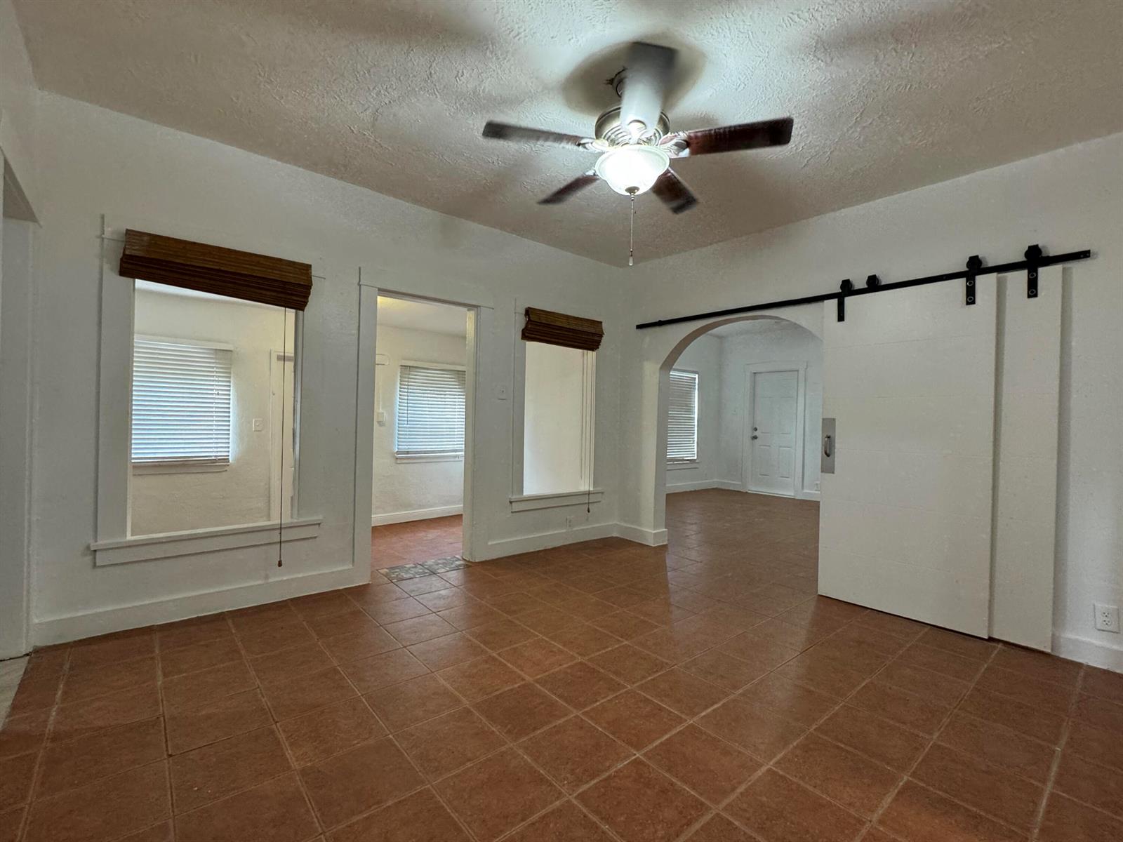 A room with terracotta tile flooring, a ceiling fan, and a white sliding barn door — 701 SW 8th Avenue, Delray Beach FL 33444, DELRAY BEACH, FL