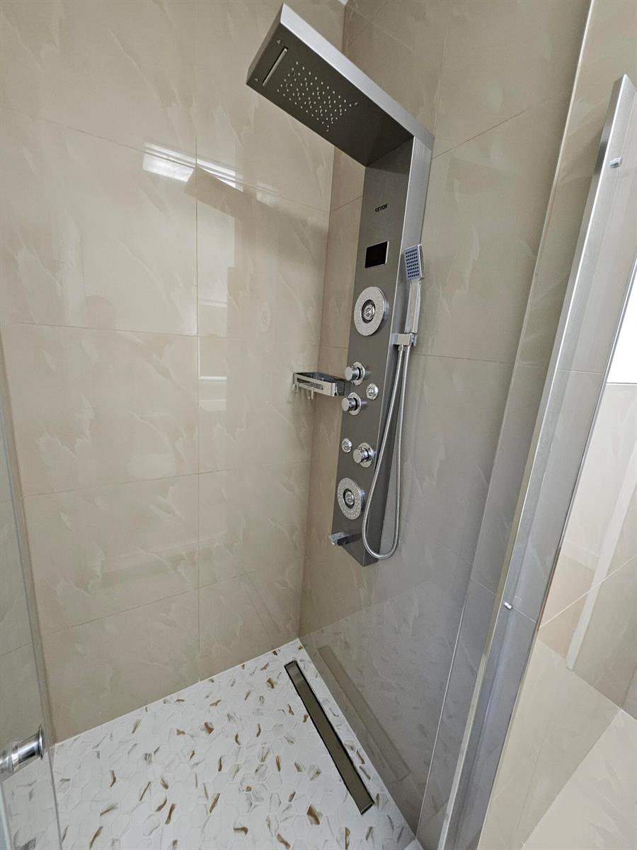 A modern shower stall features a stainless steel shower panel system and light-colored tiled walls — 701 SW 8th Avenue, Delray Beach FL 33444, DELRAY BEACH, FL