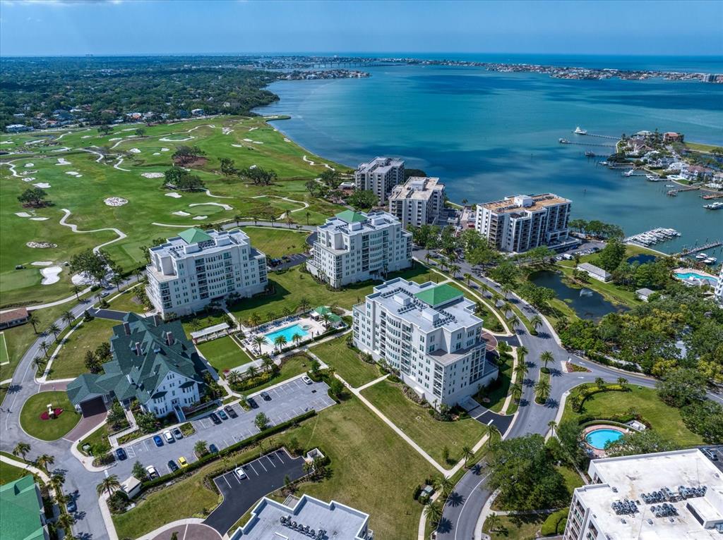 An aerial view shows several multi-story apartment buildings situated next to a golf course and water — 125 BELLEVIEW BOULEVARD UNIT 302, BELLEAIR, FL