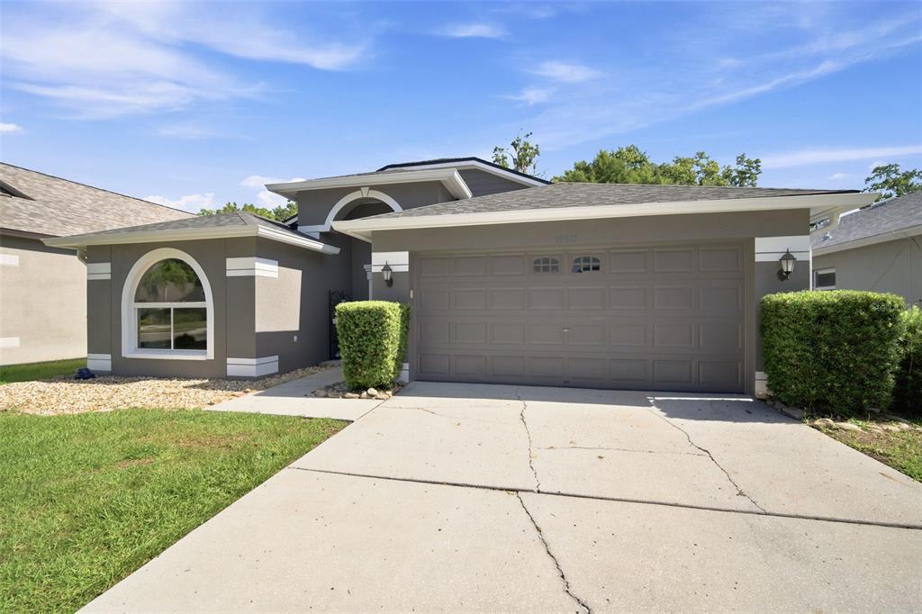 A gray single-story house with a two-car garage, arched window, and a concrete driveway — 19517 ARDWICK WAY, LAND O LAKES, FL