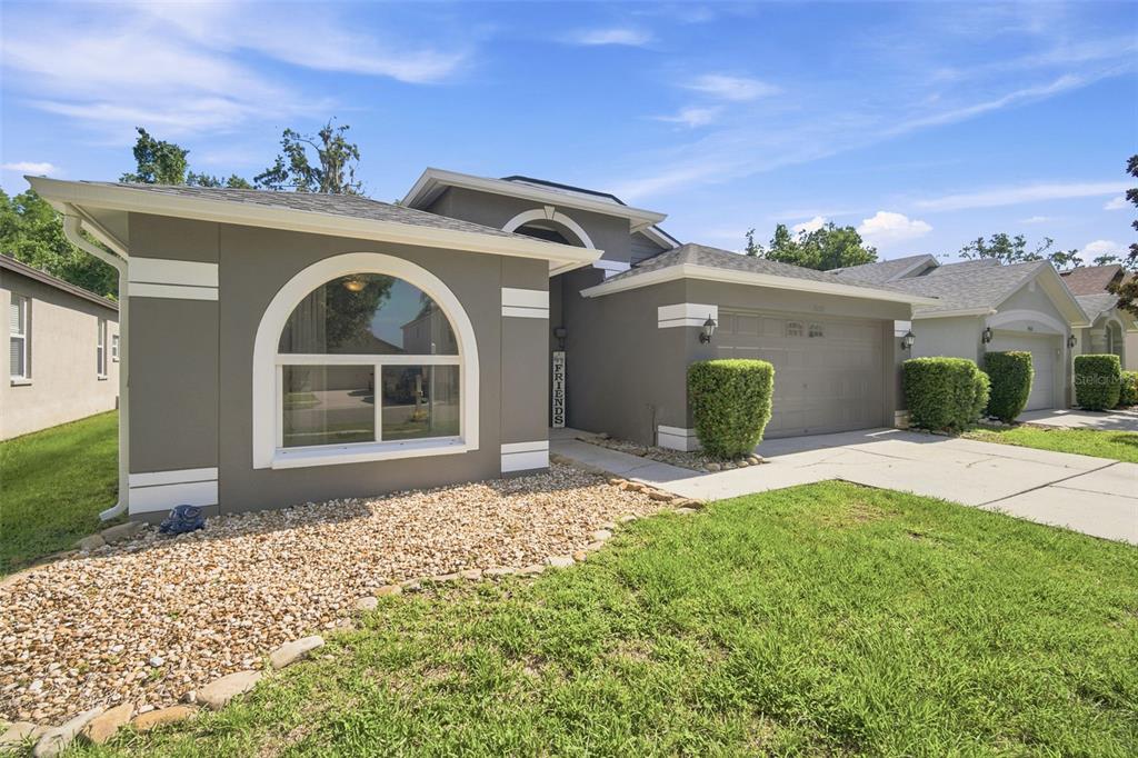 A single-story house with a gray exterior, a large arched window, and a two-car garage — 19517 ARDWICK WAY, LAND O LAKES, FL
