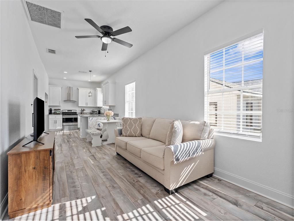 A living room with a beige sofa, wood-look flooring, and an open kitchen in the background — 2903 W IVY STREET, TAMPA, FL