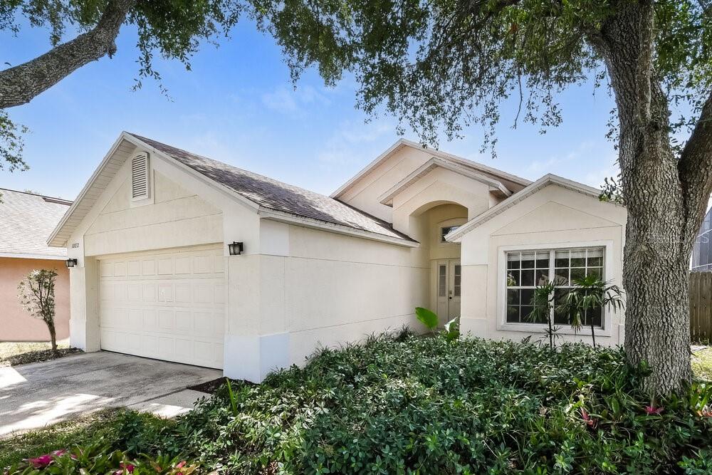 A single-story house with a white stucco exterior, a two-car garage, and a front garden — 10832 RUSHWOOD WAY, CLERMONT, FL