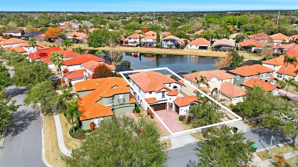 An aerial view shows a suburban house with a red tile roof near a lake — 910 LASCALA DRIVE, WINDERMERE, FL