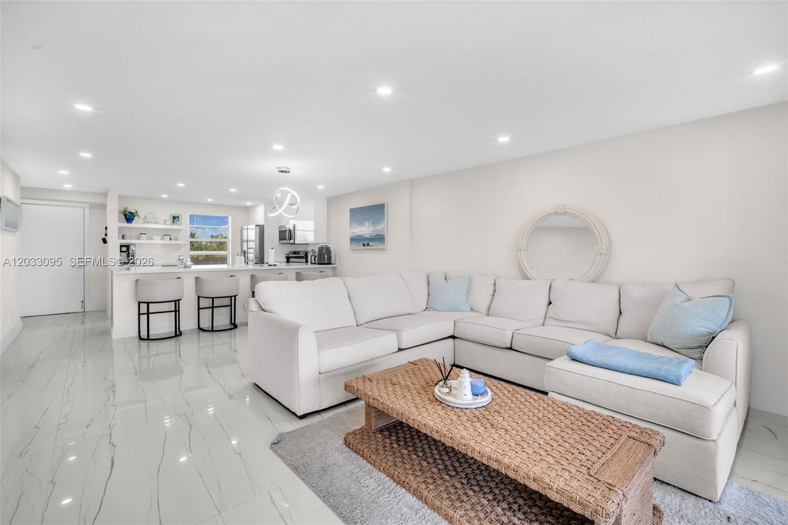 A living room features a white sectional sofa, a woven coffee table, and marble flooring — 441 SE 3rd St # 404, Dania Beach FL 33004, DANIA BEACH, FL