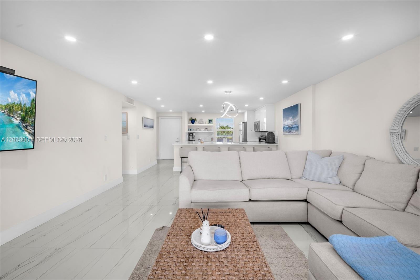 A living room features a sectional sofa, a woven coffee table, and an open kitchen — 441 SE 3rd St # 404, Dania Beach FL 33004, DANIA BEACH, FL