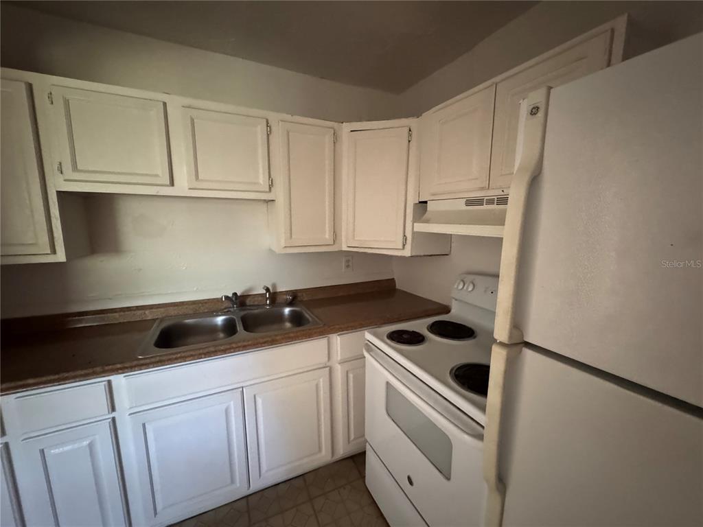 A kitchen features white cabinets, a double sink, brown countertops, and a white stove — 1131 PHELPS STREET, JACKSONVILLE, FL